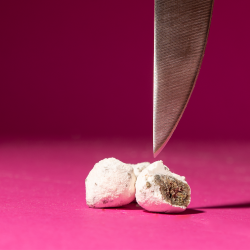 Ice rock de CBD coupée en deux par un couteau, sur fond rose