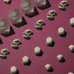 Ice rocks et ice rocks de cbd coupées en 2 posées sur une surface rose, entourées de blocs de glace