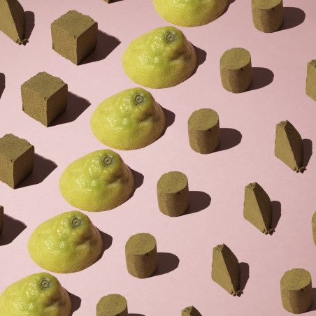 Blocs de différents formats de résines de CBD avec des citrons coupés en deux sur surface rose