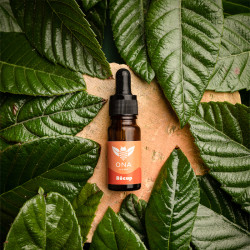 Flacon d'huile de CBD sur du bois entourée de feuilles vertes